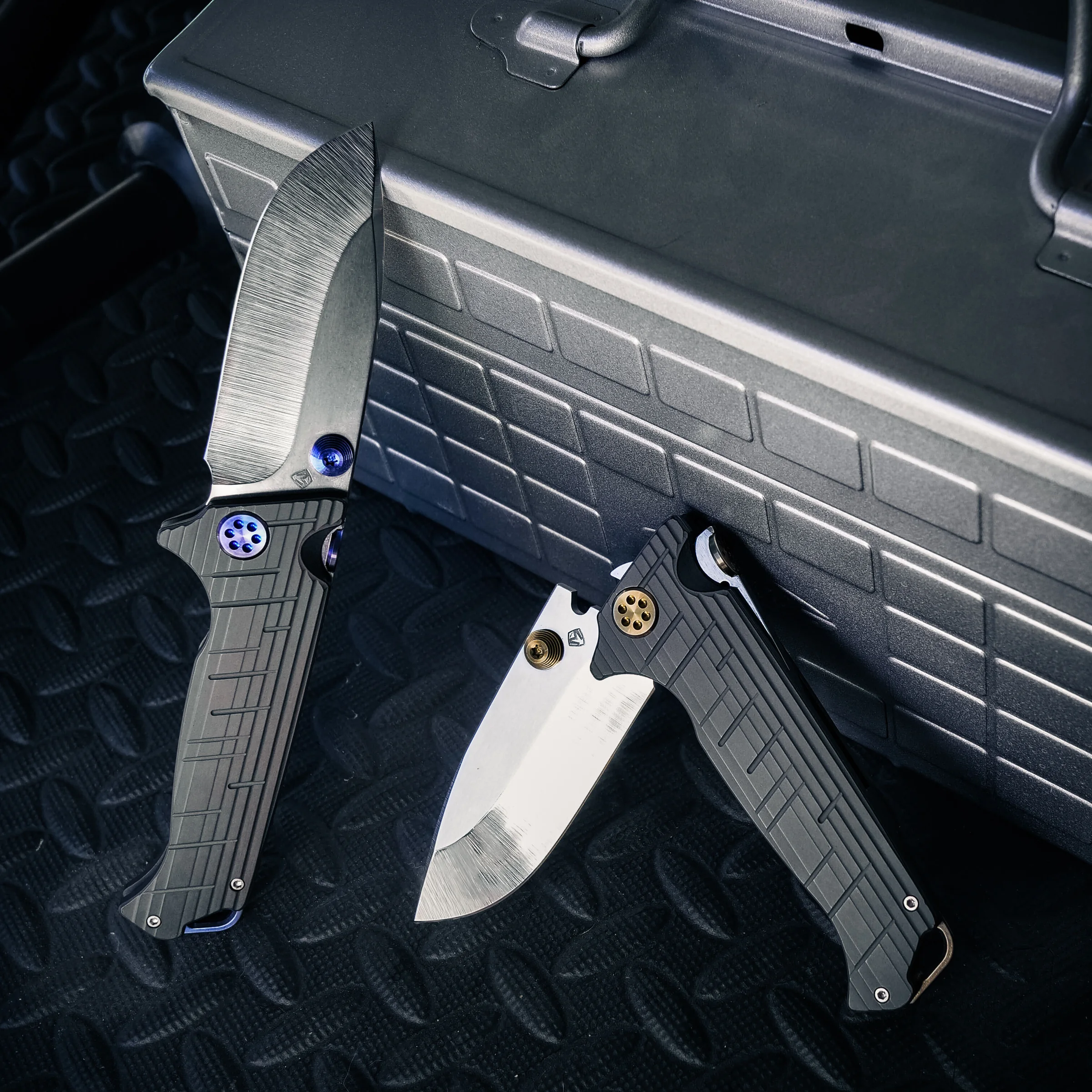 Two open Torrent knives with different hardware on a dark case