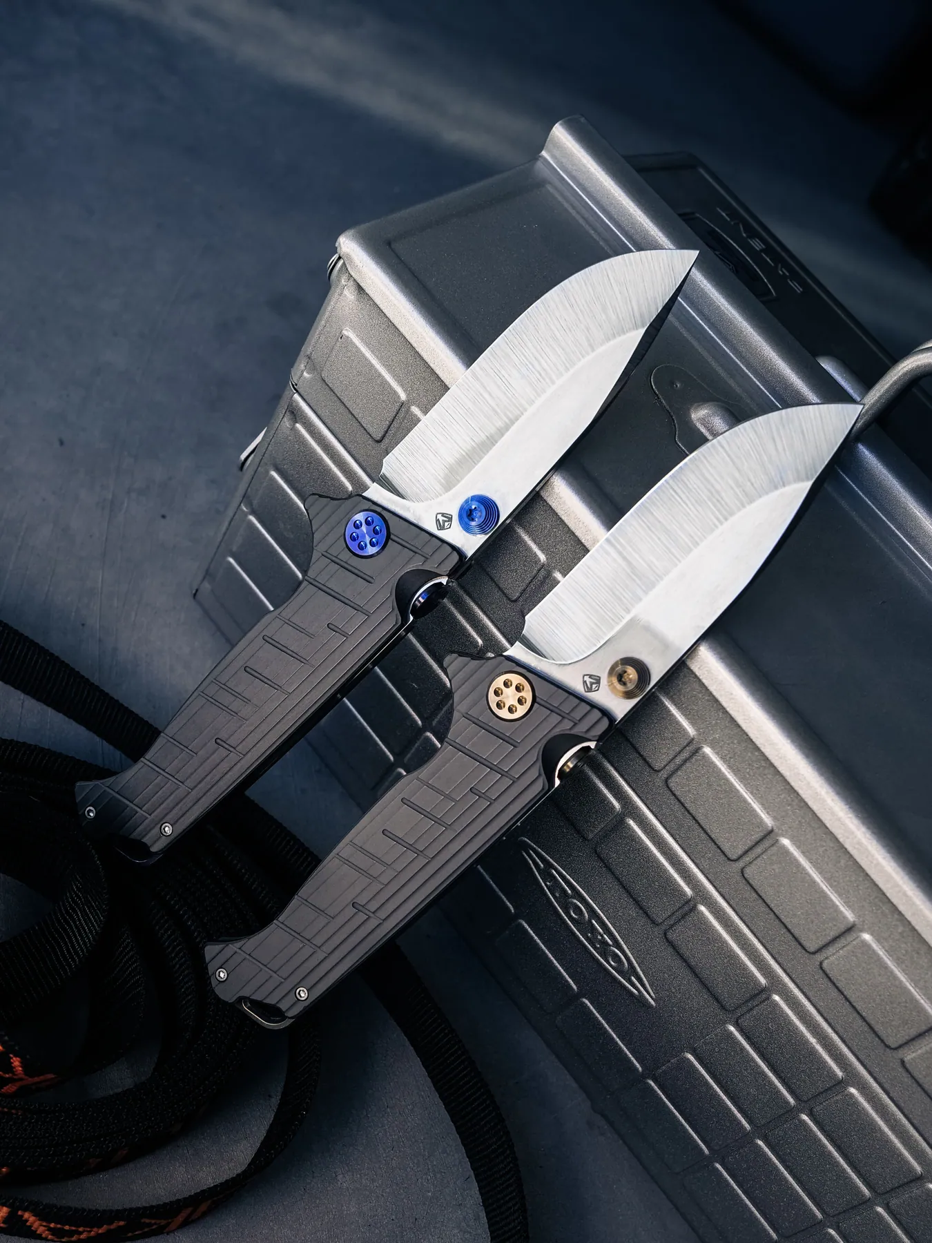 Two open Torrent knives leaning against a dark case