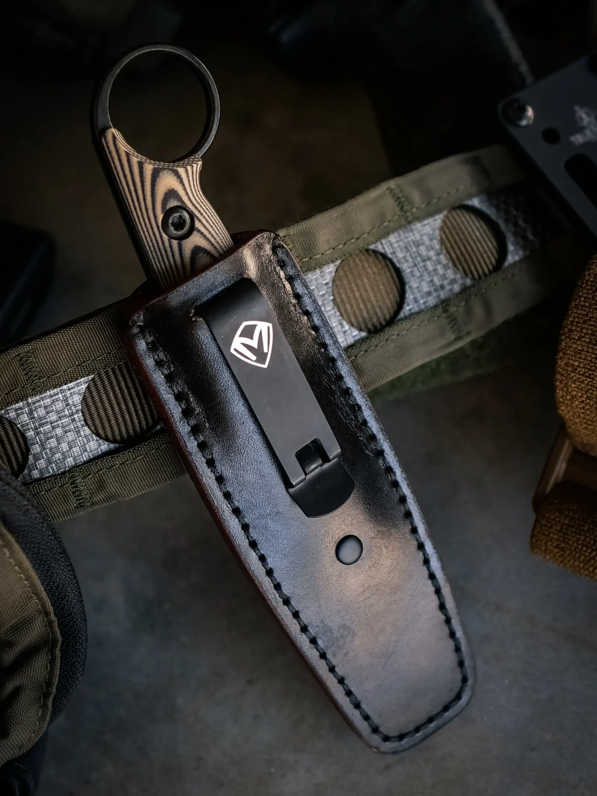 Taskmaster ringed handle seated in its black sheath on field gear